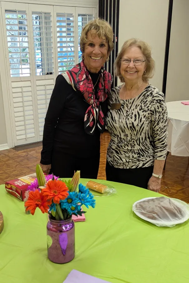 Two members at a luncheon table decorated with paper flowers.