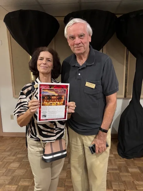 Members holding a season flyer at an event.